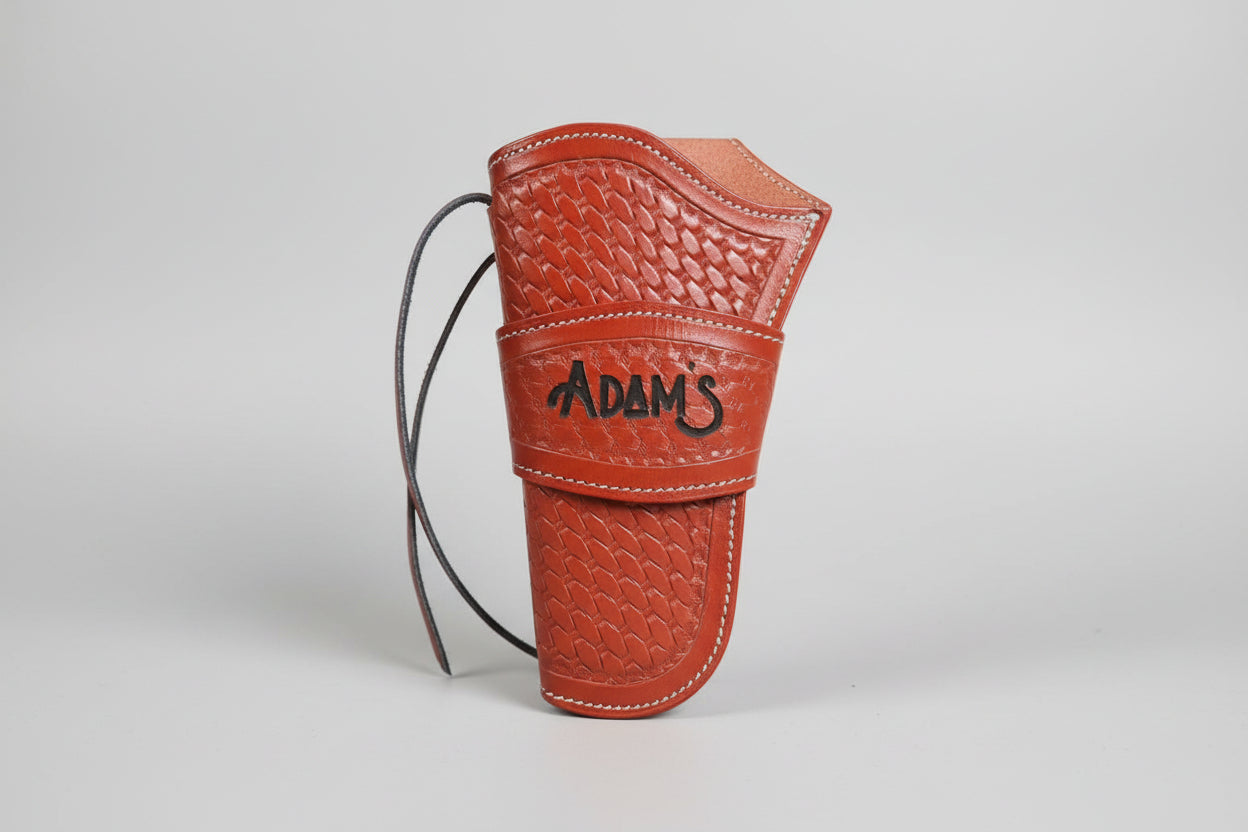 Brown leather glove with 'Adam's' branding held by a hand against a blurred indoor background